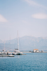 Sailing catamaran stands at the pier in the sea against the backdrop of the mountains. Back view