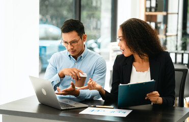 Asian business man and African American woman engaging in business discussion, possibly about...