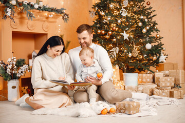 Brunette mother, father and little son sitting near Christmas tree