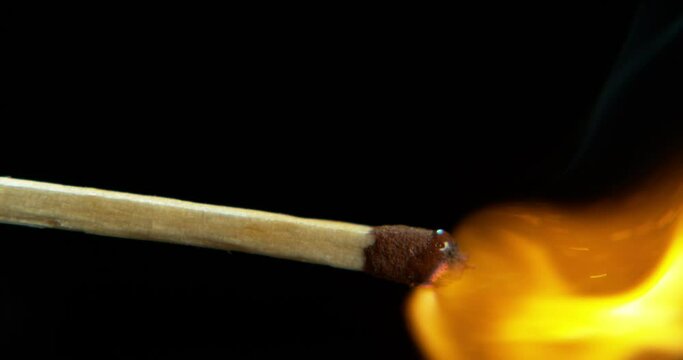 Closeup, fire and a burning match on a black background for sparks, fire or smoke. Zoom, light and a matchstick for a flame, lighting glow or passion with heat on a dark studio backdrop for danger