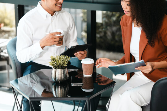 Attractive Asian businessman and African American female real estate and land investor talk discussing together on table with laptop and small building model. Reserve fund.
