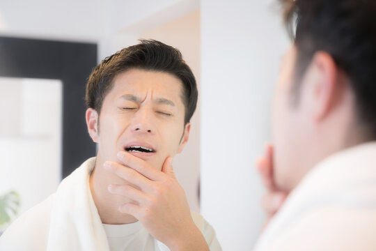  歯が痛い男性　ちょっと痛いししみるかも～知覚過敏や虫歯のイメージ