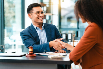 Attractive Asian businessman and an African American businesswoman, both in formal suits, intently review a contract paper together.