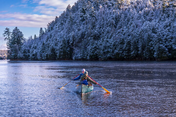 two young women paddling a green canoe on a river with trees clad in freshly fallen snow in the background room for text shot on the ottawa river in eastern ontario canada - obrazy, fototapety, plakaty