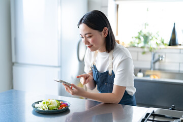料理をスマホで撮影する若い日本人女性