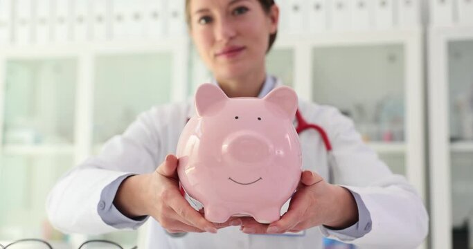 Doctor holds a piggy bank in hands in clinic