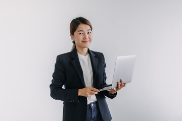 Happy asian Thai woman wear blazer holding laptop, smiling and looking at camera isolated over white background wall.