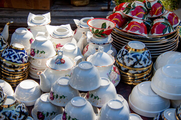 painted pottery, teapots cups and saucers and pots lie on the table for sale
