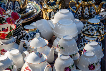 painted pottery, teapots cups and saucers and pots lie on the table for sale