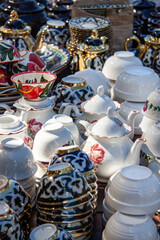 painted pottery, teapots cups and saucers and pots lie on the table for sale