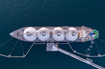 Aerial top down of Liquified Natural Gas LNG carrier moored to a small gas terminal. Fuel crisis....