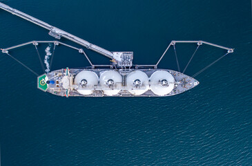 Aerial top down of Liquified Natural Gas LNG carrier moored to a small gas terminal. Fuel crisis....