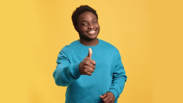 Portrait happy African man showing cool thumb up gesture recommend feedback isolated on orange