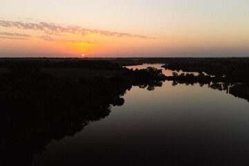 a man on a sap board swims on the lake at dawn