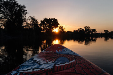 a man on a sap board swims on the lake at dawn
