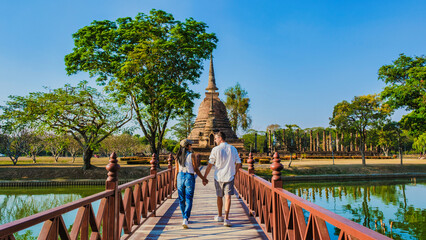 Some men and women visit Wat Sa Sit, Sukhothai Old City, Thailand. Ancient city and culture of South Asia Thailand, A couple visit Sukhothai Historical Park - obrazy, fototapety, plakaty