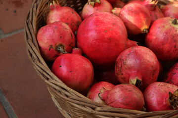 Fototapeta na wymiar Close-up of red ripe Pomegranate fruits in a wicker basket. Punica granatum
