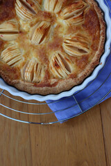 Top view of tasty apple pie with cream and sliced fruits on wooden table