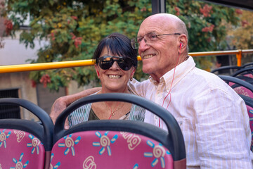 Senior happy caucasian couple sitting on sightseeing open-top bus visiting city of Cordoba,...