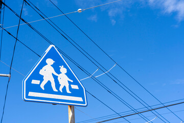 横断歩道を示す標識と街に張り巡らされた電線