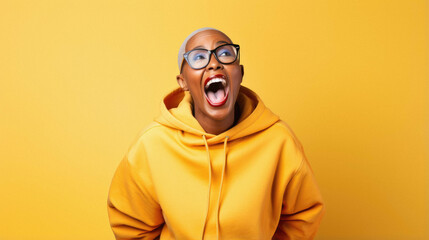 Obraz premium Portrait of a happy young african woman with glasses in yellow jacket on yellow background.