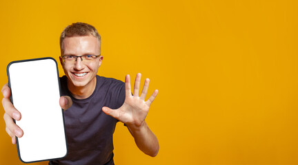 Handsome man showing five fingers and holding smartphone with empty white screen display for new...
