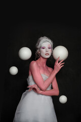 Glamorous model woman with white planet spheres on black background. Astrology, magic, fantastic and space concept