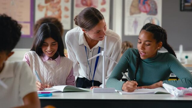 Female teacher helping secondary or high school students studying wind turbines in science class - shot in slow motion