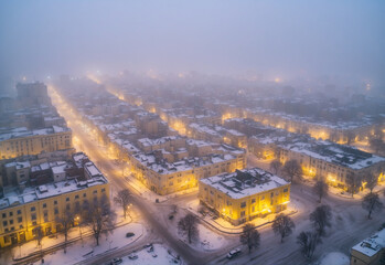 Center of the city in winter. At night and foggy. Drone point of view. The light is yellow. quiet without people - obrazy, fototapety, plakaty