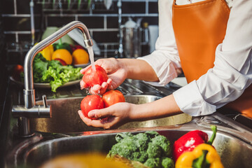 Hand of maid washing tomato fresh vegetables preparation healthy food in kitchen