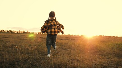 Little girl dressed in casual clothes runs through field and revels present moment
