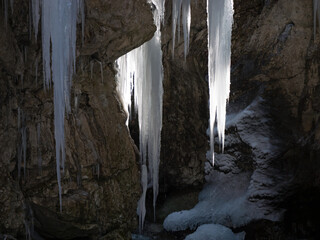 CLOSE UP: Glorious icicles hang above alpine stream flowing through narrow gorge