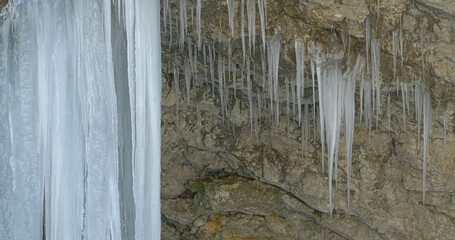 CLOSE UP: Enormous icicles hang from an overhang in a narrow Mostnica Gorge