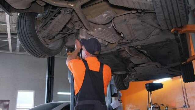 A mechanic repairs the chassis of a car. Car workshop