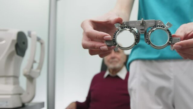 Ophthalmologist makes a selection of lenses, diagnoses a elderly senior man's vision on a sign projector. The concept of testing and vision correction using new medical technologies. 