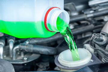 Close-up of pouring coolant antifreeze fluid in workshop. Checks and periodic maintenance of cars.	