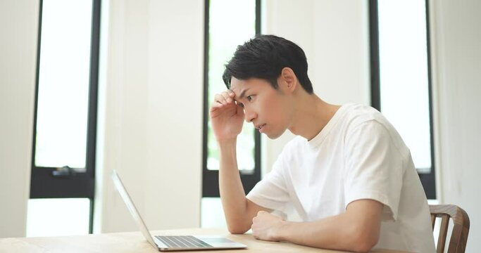 ノートパソコンを見て悔しがる男性