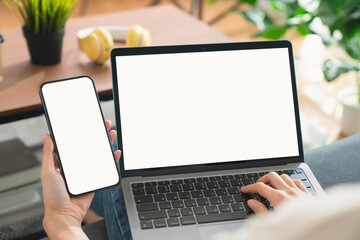 Hand holding smartphone with laptop mockup of blank screen, Take your screen to put on advertising.