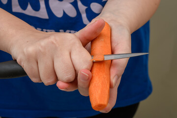 Kobieta obiera marchew nożem kuchennym - obrazy, fototapety, plakaty