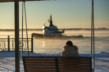 A woman watches sea tugs in winter on the embankment. High quality photo