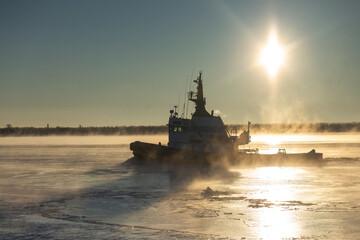 The tugboat breaks the ice near the shore in a foggy frozen river. High quality photo