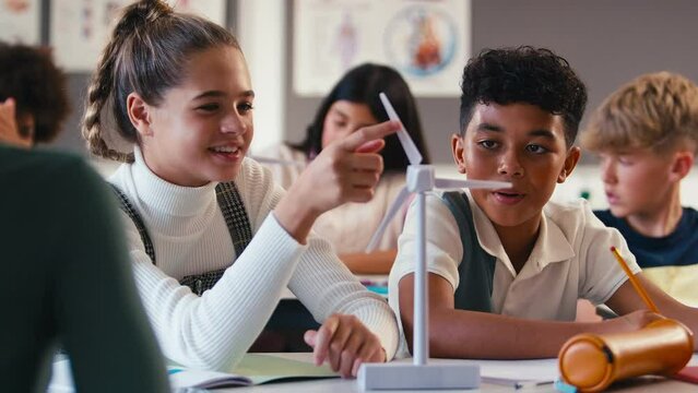 Secondary or high school students studying wind turbines in science class with female teacher in background - shot in slow motion