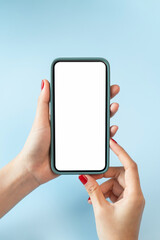 Female hands holding smartphone with mockup of blank screen on blue background.