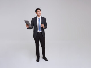 Handsome and friendly face asian businessman smile in formal suit his using tablet and holdinf coffee cup isolated on white background studio shot.