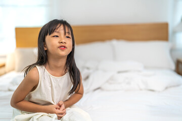 Portrait of sick unhappy little child asian girl touching belly stomach with suffering from stomach...