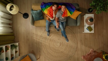 Top view shot of a homosexual couple sitting on the couch together, looking up at the camera...