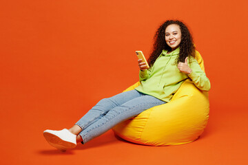 Full body happy young woman of African American ethnicity she wear green hoody casual clothes sit...