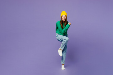 Full body young woman she wear green sweater yellow hat casual clothes stand on toes with...