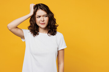 Young sad mistaken confused Caucasian woman she wear white blank t-shirt casual clothes scratch head look aside on area isolated on plain yellow orange background studio portrait. Lifestyle concept. - obrazy, fototapety, plakaty