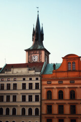 A clock tower in Prague with a red roof and a blue sky.
